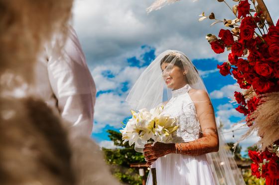 Bride in a veil holding her bouquet by the arch
