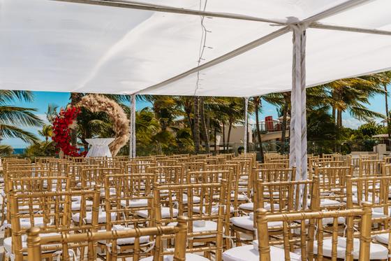 Gold chiavari chairs set under a white canopy before the ceremony