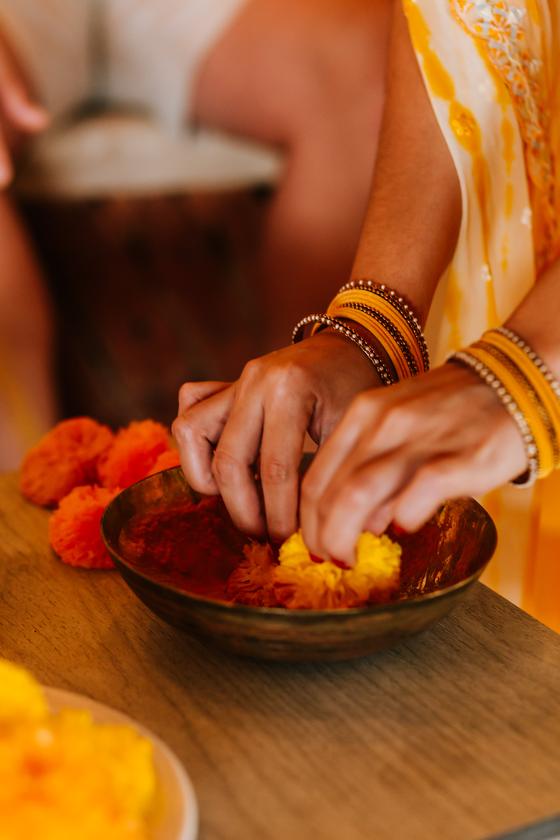 Hands reaching into the bowl of turmeric paste