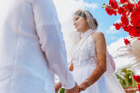 Bride beside the red roses of the arch