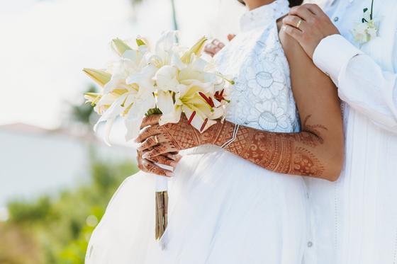 Bouquet and henna-covered hands as the couple embrace