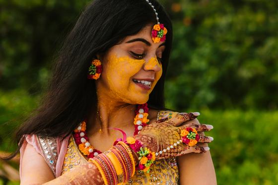 Bride in yellow with floral jewellery, eyes lowered