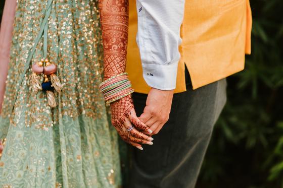 Henna-covered hand held against a yellow sleeve