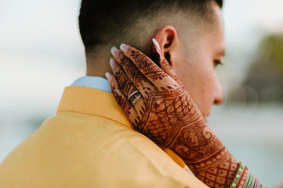 Henna-covered hand resting on the groom's shoulder