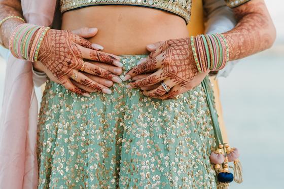 Henna-covered hands clasped at the bride's waist