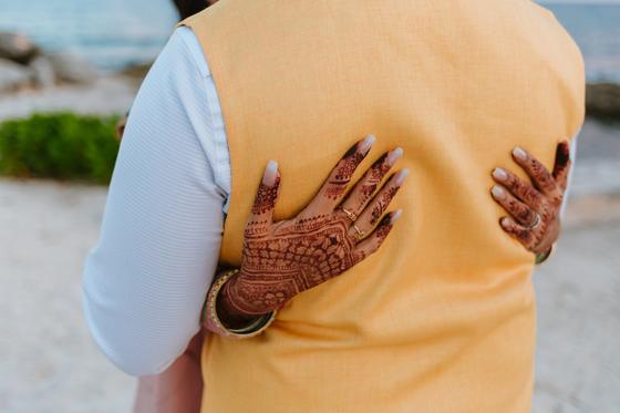Henna-covered hands resting on a yellow nehru vest