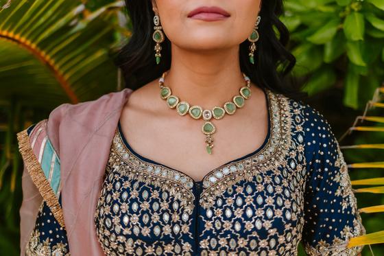 Carved emerald and gold necklace against a printed blouse