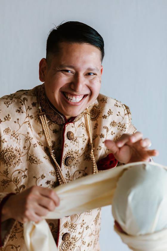 Groom laughing in an ivory and gold sherwani