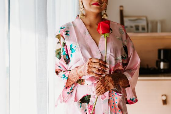 Bride holding a single red rose by a bright window