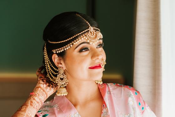 Bride smiling in a floral robe before dressing