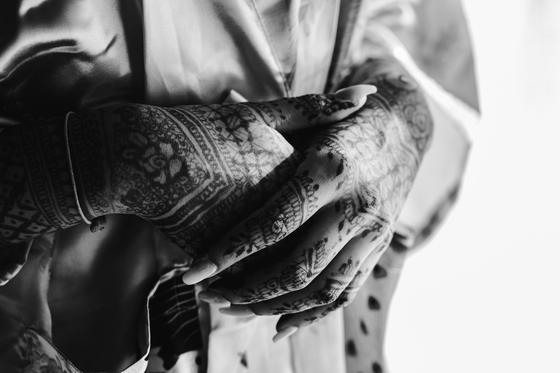 Black and white detail of henna-covered hands
