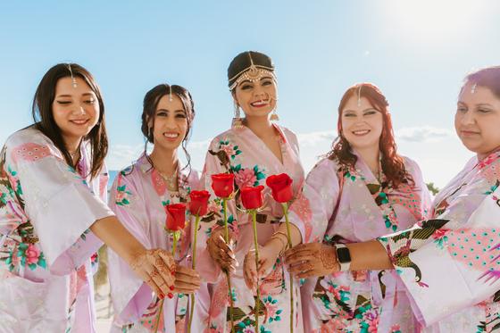 Bridal party holding red roses above the resort gardens