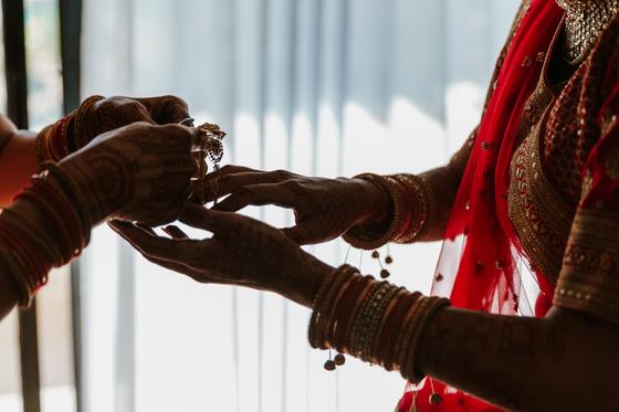 Henna-covered hands lifting a gold bangle