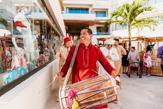 Dhol player drumming through the baraat procession
