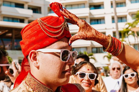 Groom in a red safa and sunglasses during the baraat