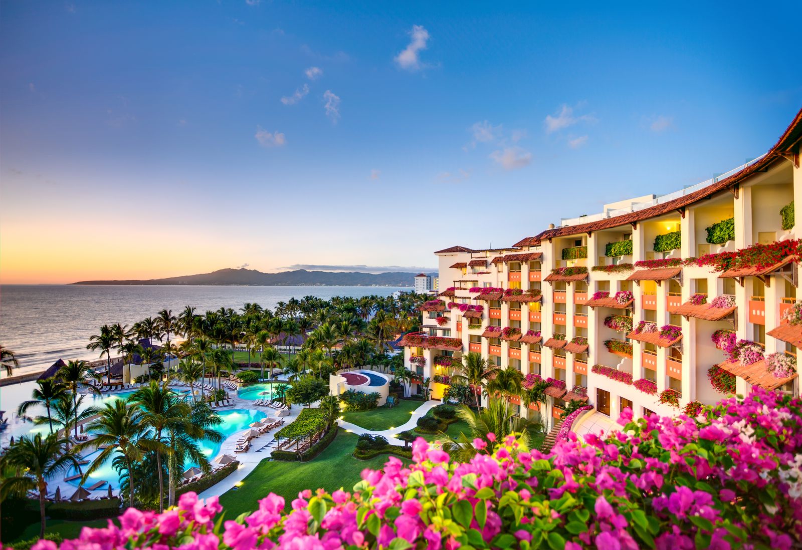 A resort terrace above pools and palms at the edge of the bay