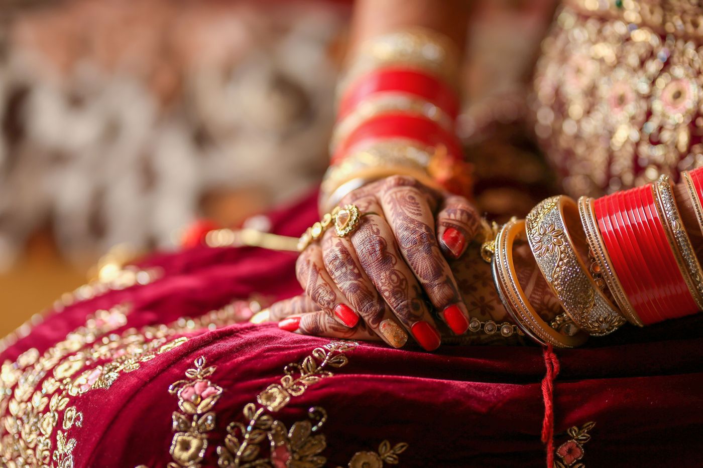 A bride’s hennaed hands and red chooda bangles